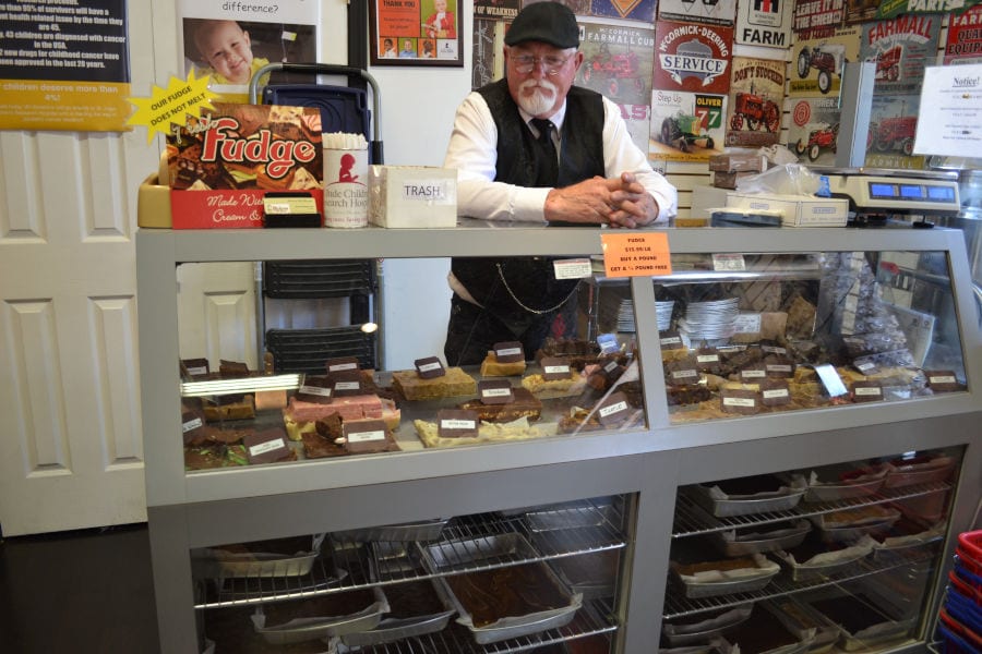 man at Dicken's Gift check out with the a large variety of fudge on display