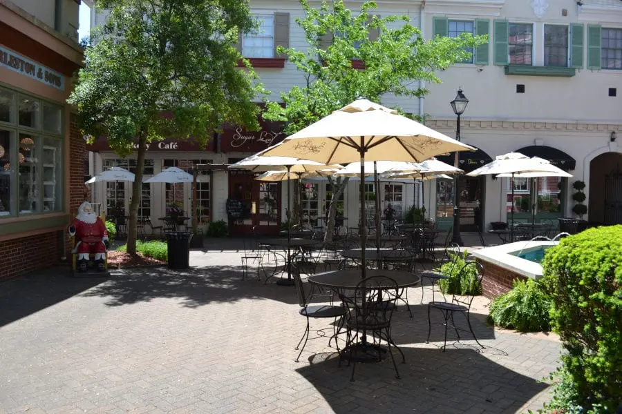 sitting area at Grand Village Shops with patio tables, a fountain, and umbrellas for shaded seating